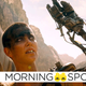 Charlize Theron's Furiosa raises her hands above her head in a scene from Mad Max: Fury Road.